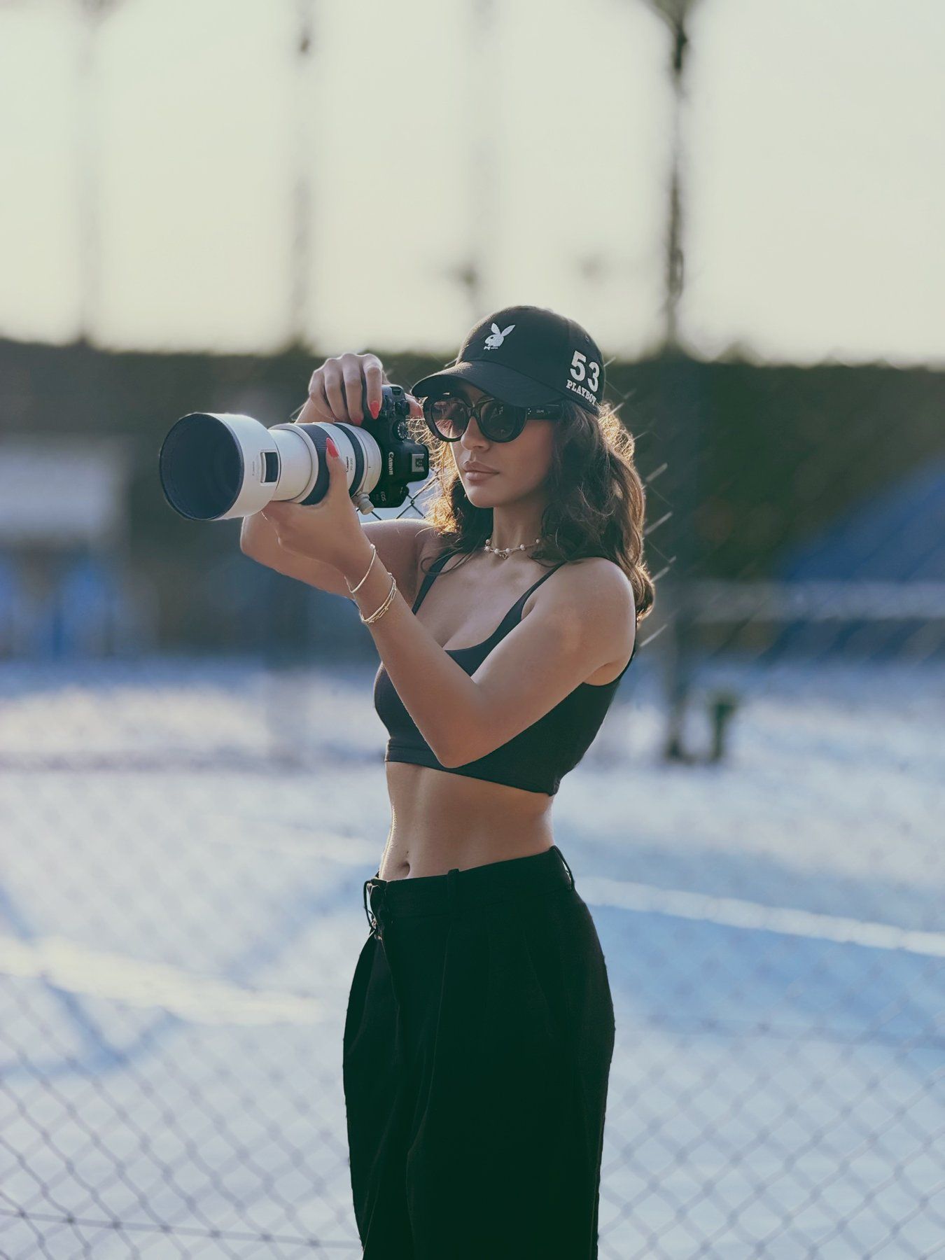 Vida Akbari holding a Canon camera with a telephoto lens, shooting in golden backlight